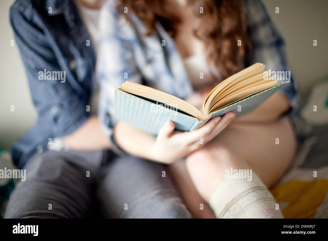 USA, Massachusetts, Mittelteil des jungen Paares auf Bett lesen Stockfoto