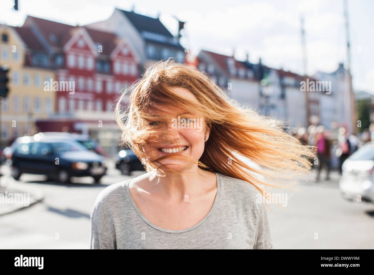 Portrait von glücklich Frau mit windigen Haare auf Stadtstraße Stockfoto
