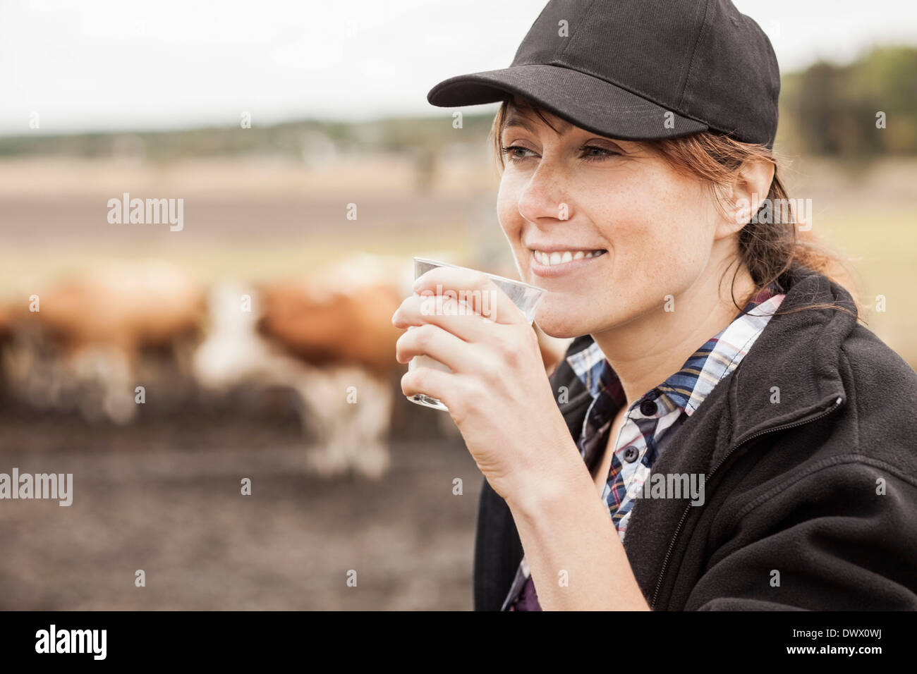 Mitte adult Bäuerin Trinkmilch in Hof Stockfoto