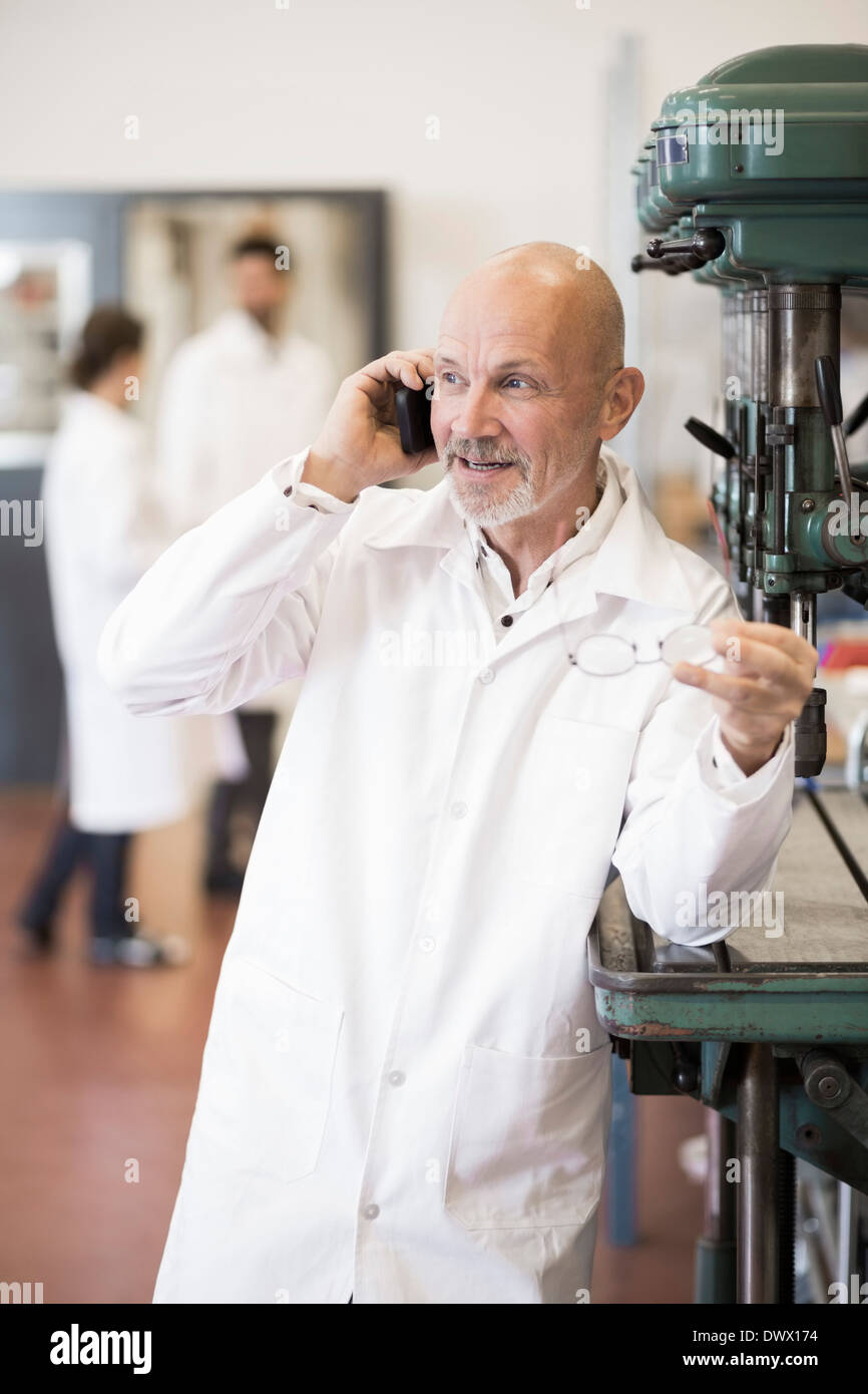 Antwortenden Handy mit Kollegen im Hintergrund bei Industrie-Ingenieur Stockfoto