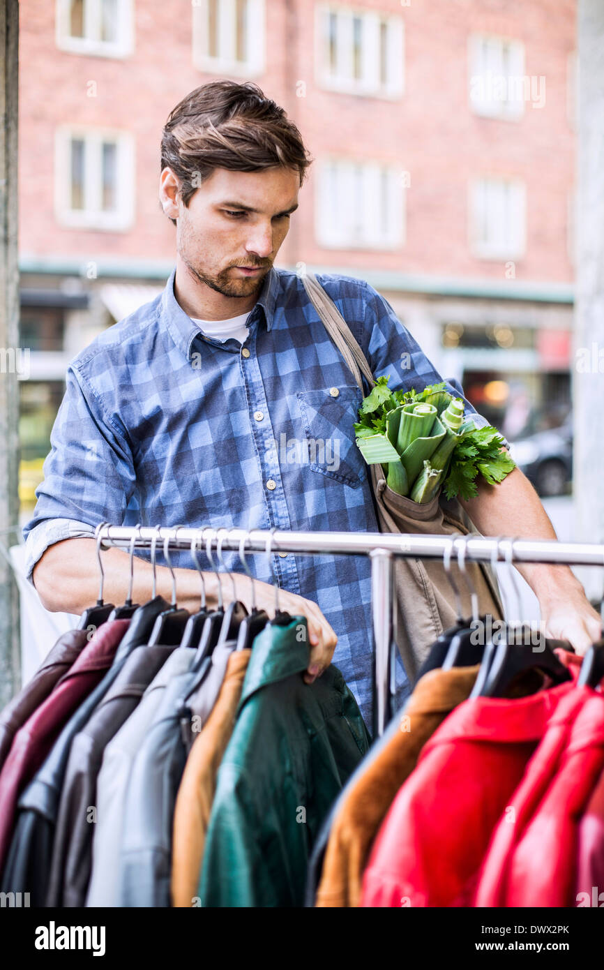 Junger Mann mit Lebensmittel-Auswahl von Jacken in Bekleidungsgeschäft Stockfoto
