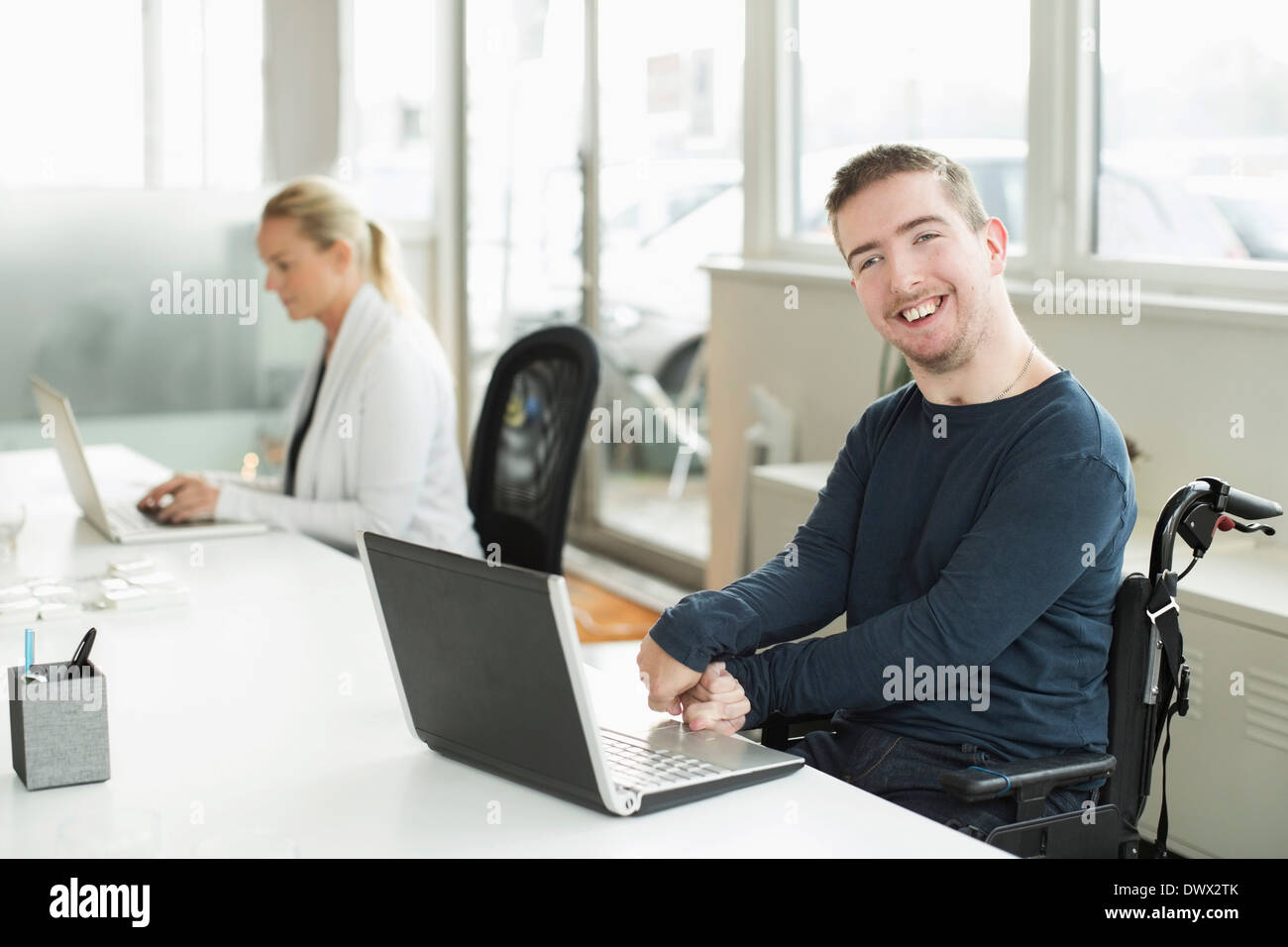 Porträt von glücklich Kaufmann mit zerebraler Lähmung mit Laptop im Büro Stockfoto