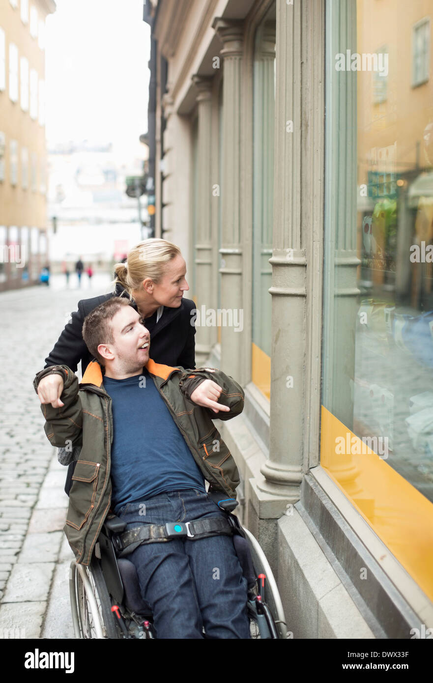 Behinderte Menschen im Rollstuhl Witwe Einkaufen mit Hausmeister Stockfoto