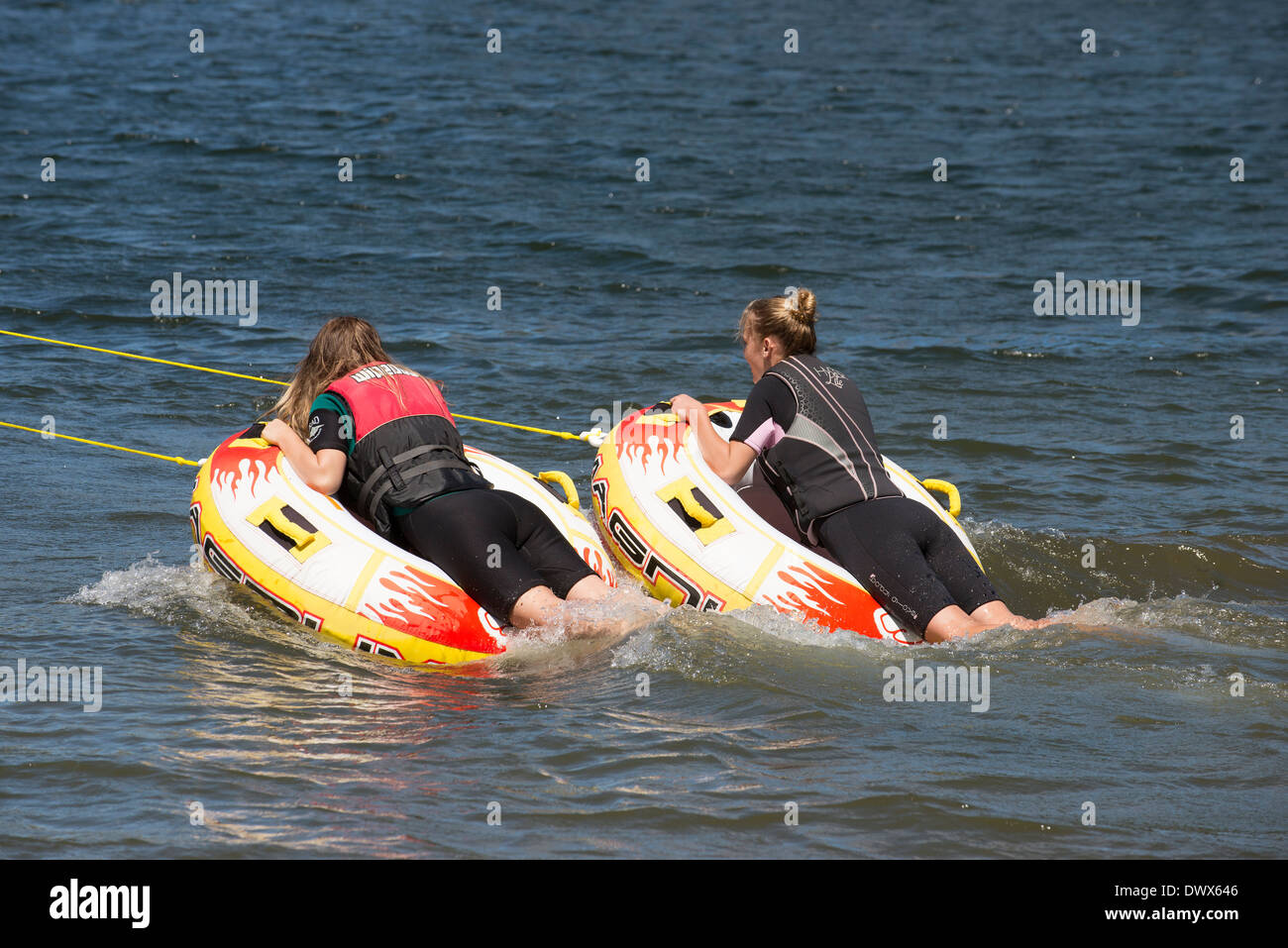 Zwei Mädchen im Teenageralter fahren aufblasbaren Donut, gezogen von einem Schnellboot an einem Fluss in der Moana Roa Reserve North Island NZ Stockfoto