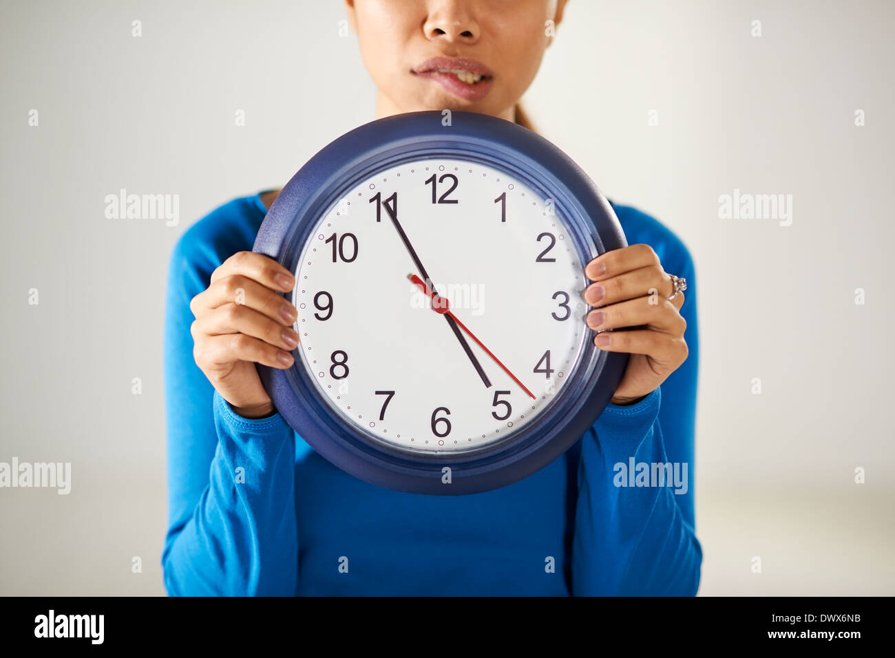 Porträt von asiatischen Geschäftsfrau hält große blaue Armbanduhr und Blick in die Kamera mit Sorge Ausdruck Stockfoto