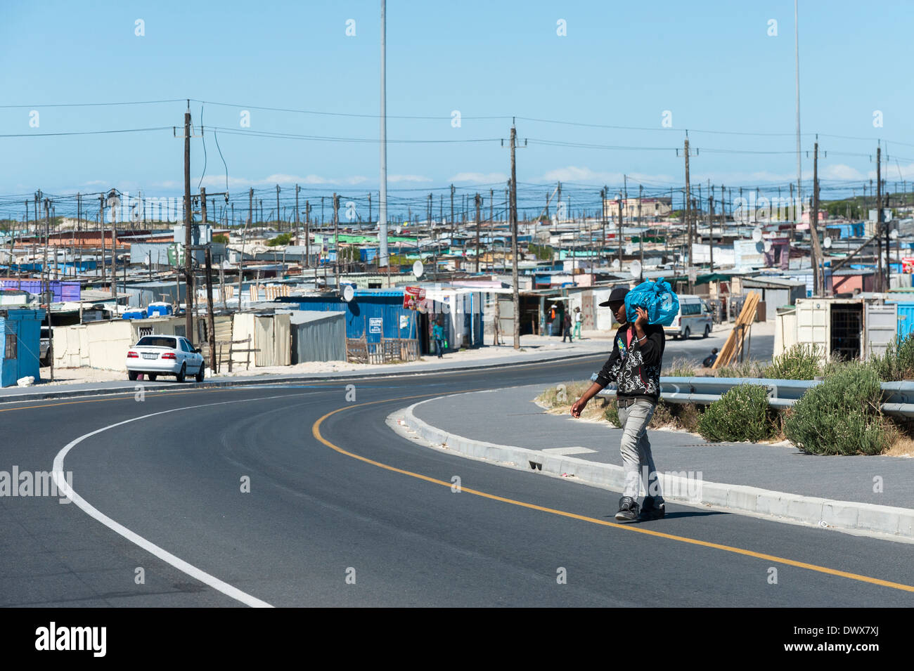 Mann mit einer Tasche kreuzt eine Straße in Khayelitsha, Kapstadt, Western Cape, Südafrika Stockfoto