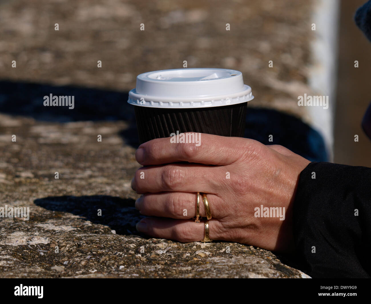 Alte Frau Hand hält eine Take away Tasse Kaffee, UK Stockfoto