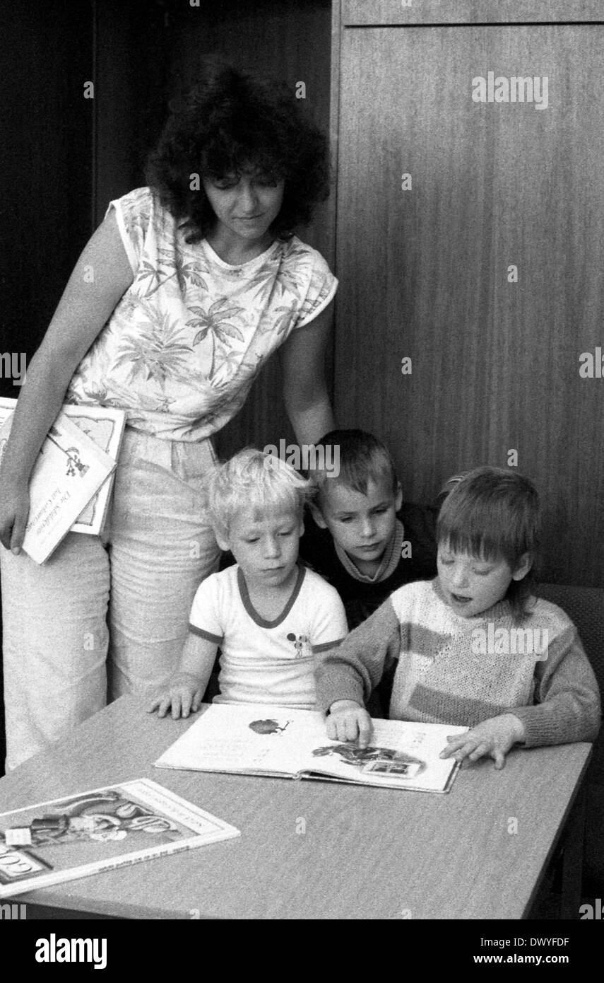 Berlin, DDR, Kinder im Vorschulalter schauen Sie sich eine Bibliothek ein Buch auf Stockfoto
