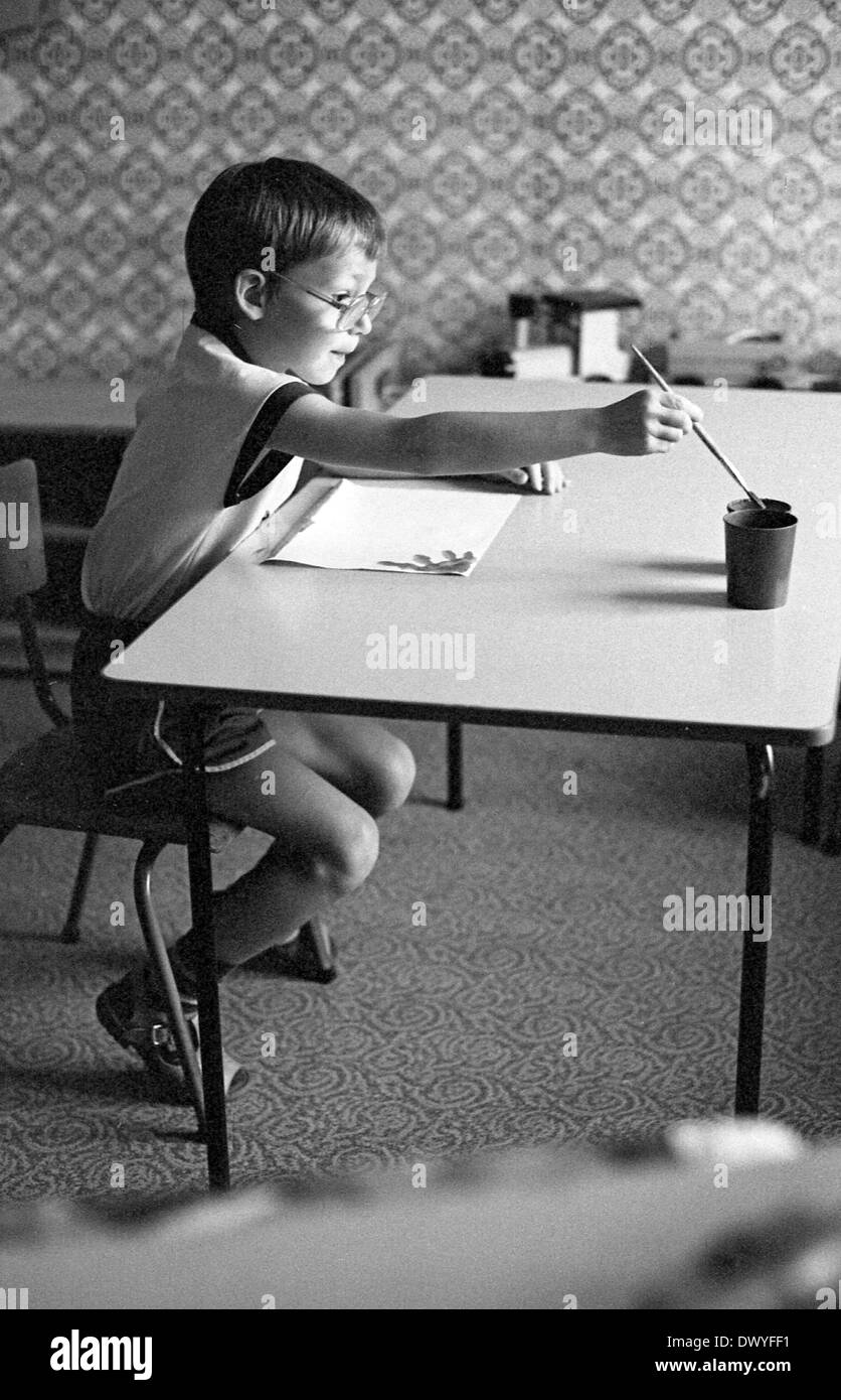 Berlin, DDR, ein kleiner Junge sitzt an einem Tisch und malt ein Bild mit Aquarellfarben Stockfoto