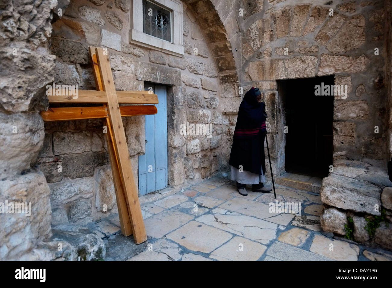 Ein äthiopisch-orthodoxe Christ steht neben Kreuzungen, die den Ort der 10. Kreuzungsstation nahe dem Eingang zur äthiopisch-orthodoxen Kammer am Parvis oder Parvise der Grabeskirche in der christlichen Viertel-Altstadt von Ostjerusalem Israel markieren Stockfoto