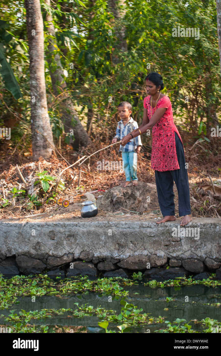 Süd Süd Indien Kerala Backwaters Tour cruise Wasserstraße Kanal Frau Angeln mit hausgemachten Bambus-Stab von junge junge Sohn Stockfoto