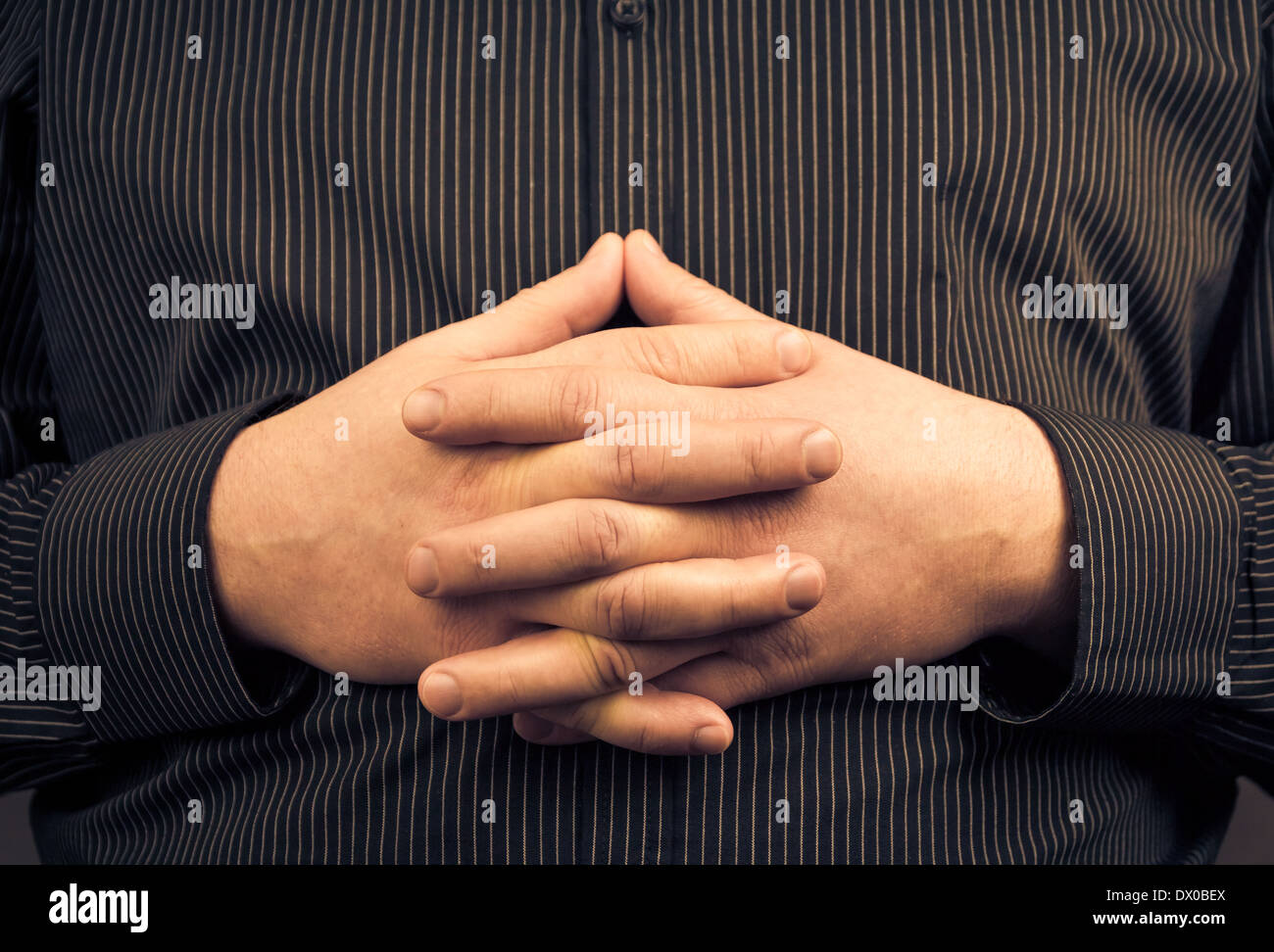 Ein Mann trägt ein Shirt mit gefalteten Händen Stockfoto