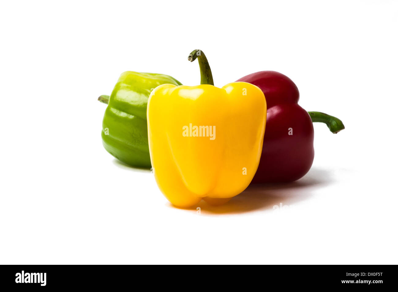 Drei süße Paprika rote, gelbe und grüne Farbe. Gelbe Paprika ist ein Hauptziel. Zwei andere Paprika stehen dahinter. Isoliert. Stockfoto