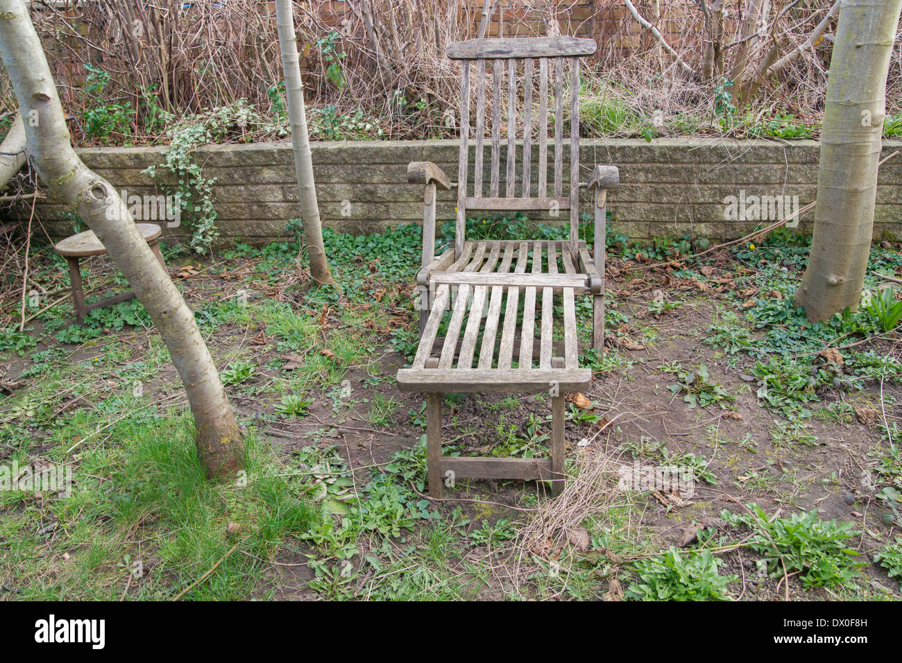 Stuhl aus Holz liege im Garten neben Bäumen Stockfoto