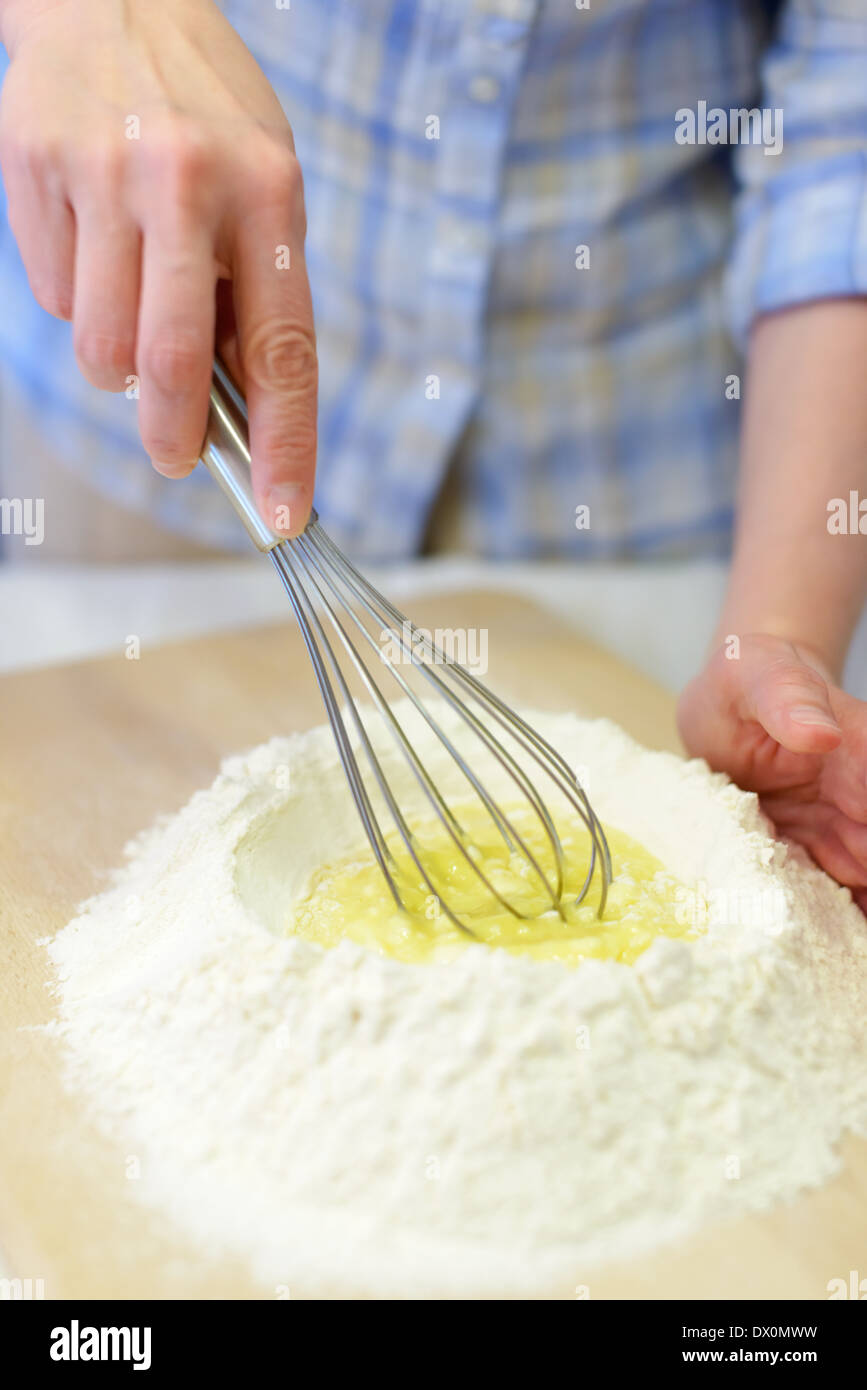 Kochen: Frau Teig, Hinzufügen von Eiern zum Mehl Stockfoto