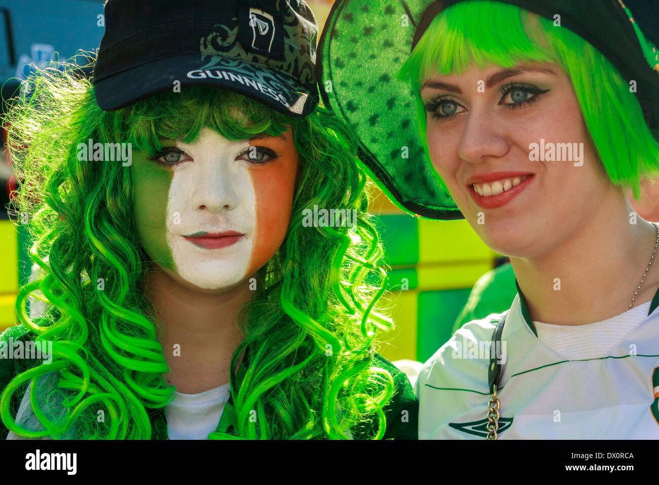Zwei junge Frauen, eine mit ihrem Gesicht in den Farben der irischen Tricolor, während der Feierlichkeiten zum St. Patrick's Day. Stockfoto