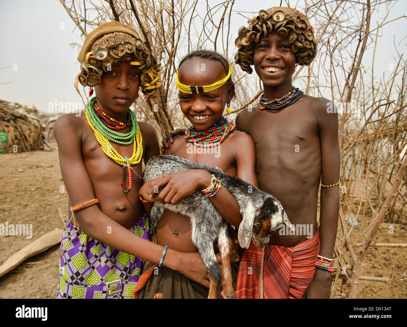 Dassanech Kinder mit Flasche Kappe Schmuck und Ziege im unteren Omo-Tal von Äthiopien Stockfoto