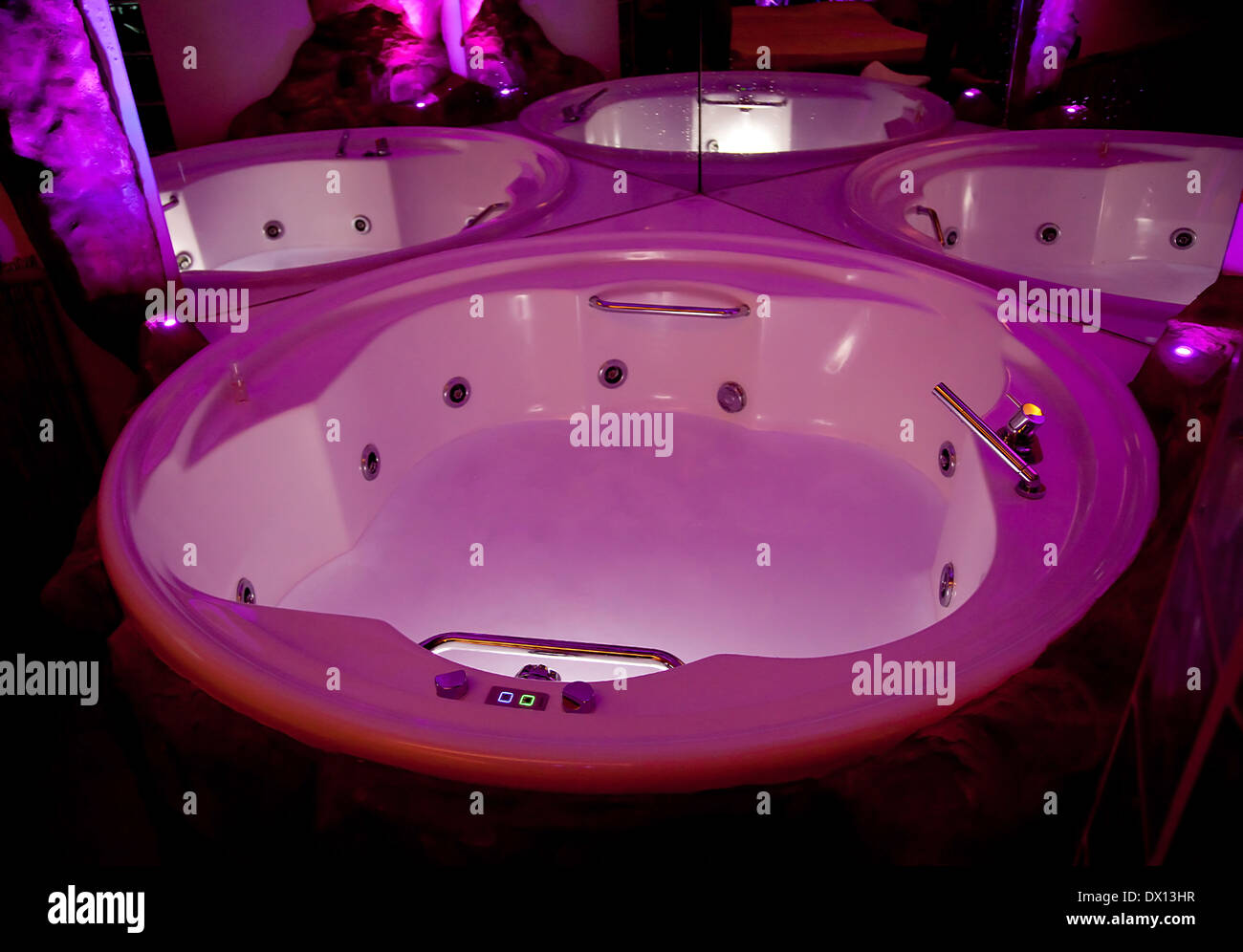 Weiße Whirlpool-Badewanne mit Rock und rosa Licht für Farb-Therapie. Stockfoto