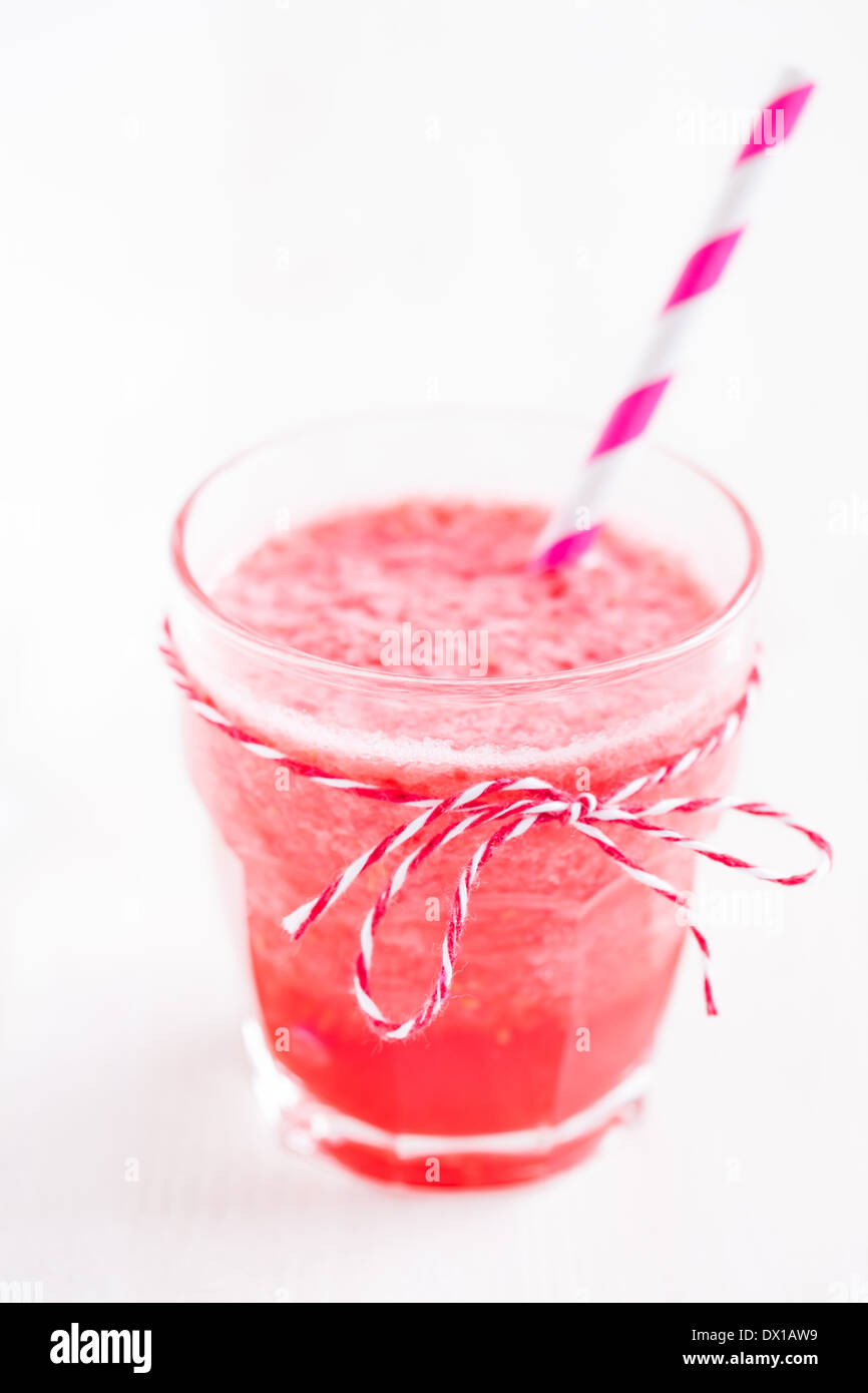 Nahaufnahme von Erdbeer Smoothie und gestreiften Stroh in Glas auf hellem Hintergrund Stockfoto