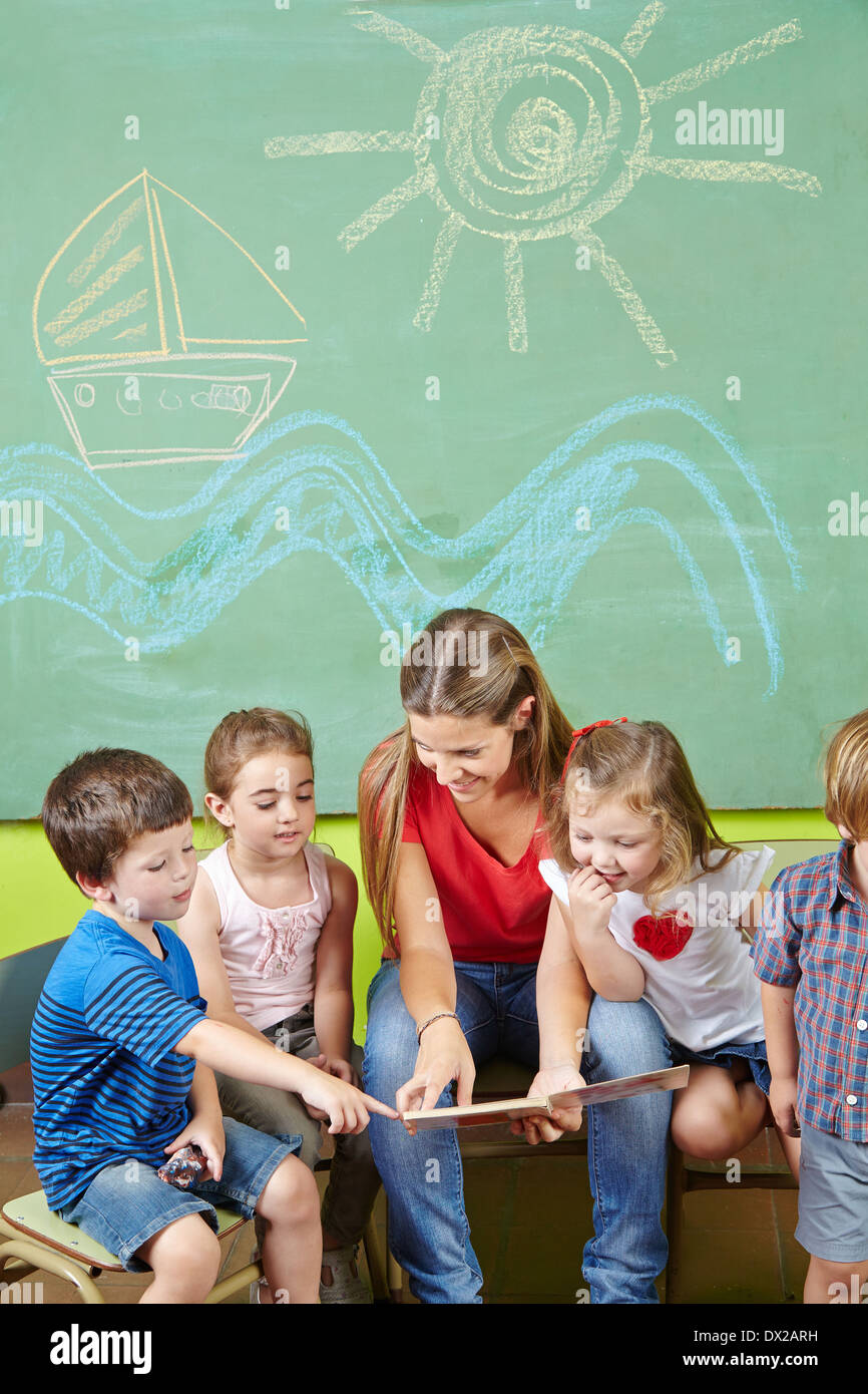 Kinder im Vorschulalter Lesebuch zusammen mit einer Kindergärtnerin Stockfoto