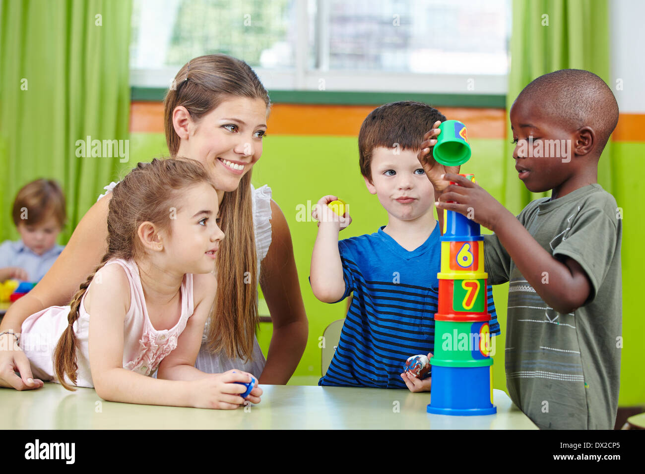 Kinder mit Kindergärtnerin Turm in eine Kindergartengruppe zu bauen Stockfoto