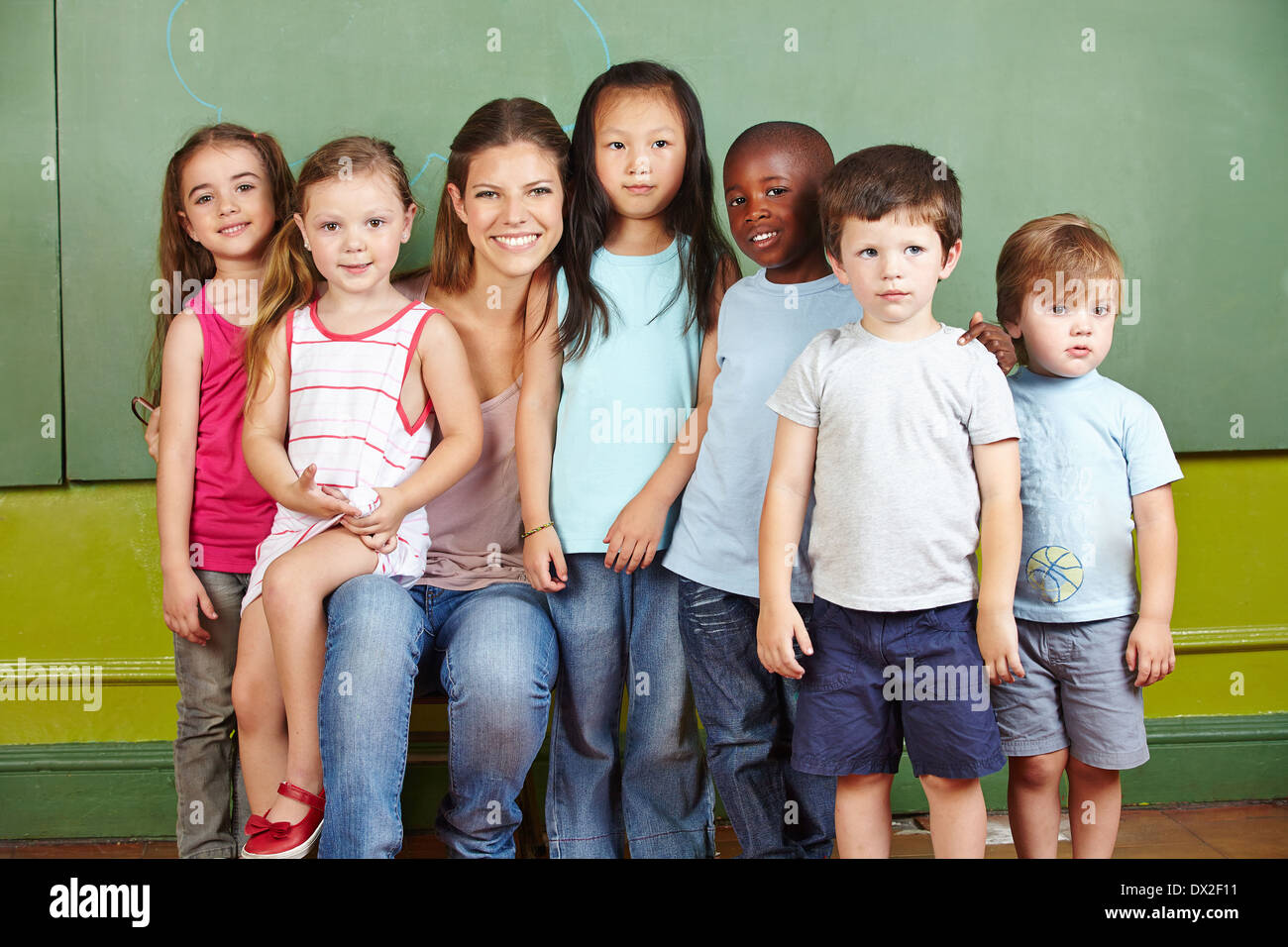 Glückliche Gruppe von Kindern mit lächelnden Kindergärtnerin in einem Raum Stockfoto