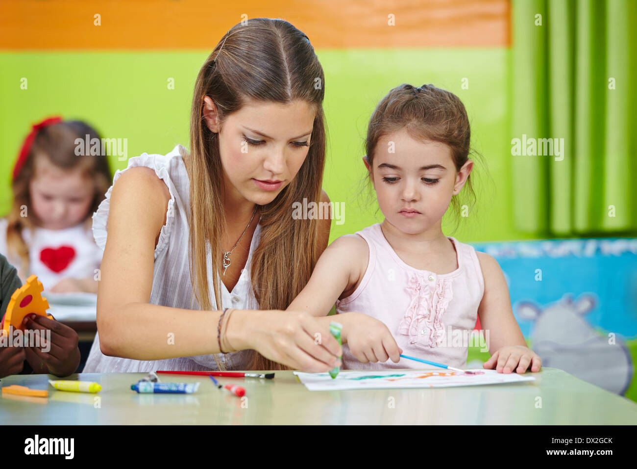 Kindergarten Lehrer helfen Mädchen malen mit Aquarell in einem kindergarten Stockfoto