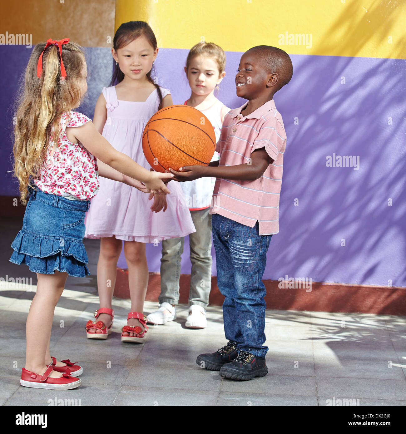 Interracial Gruppe von Kindern zusammen mit Basketball im Kindergarten spielen Stockfoto