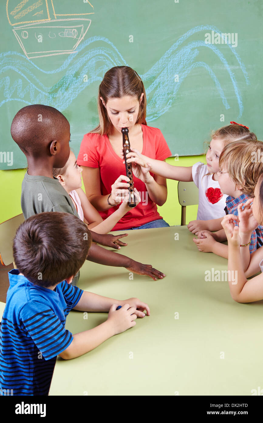 Kindergärtnerin Flötenspiel für Kinder in einem kindergarten Stockfoto