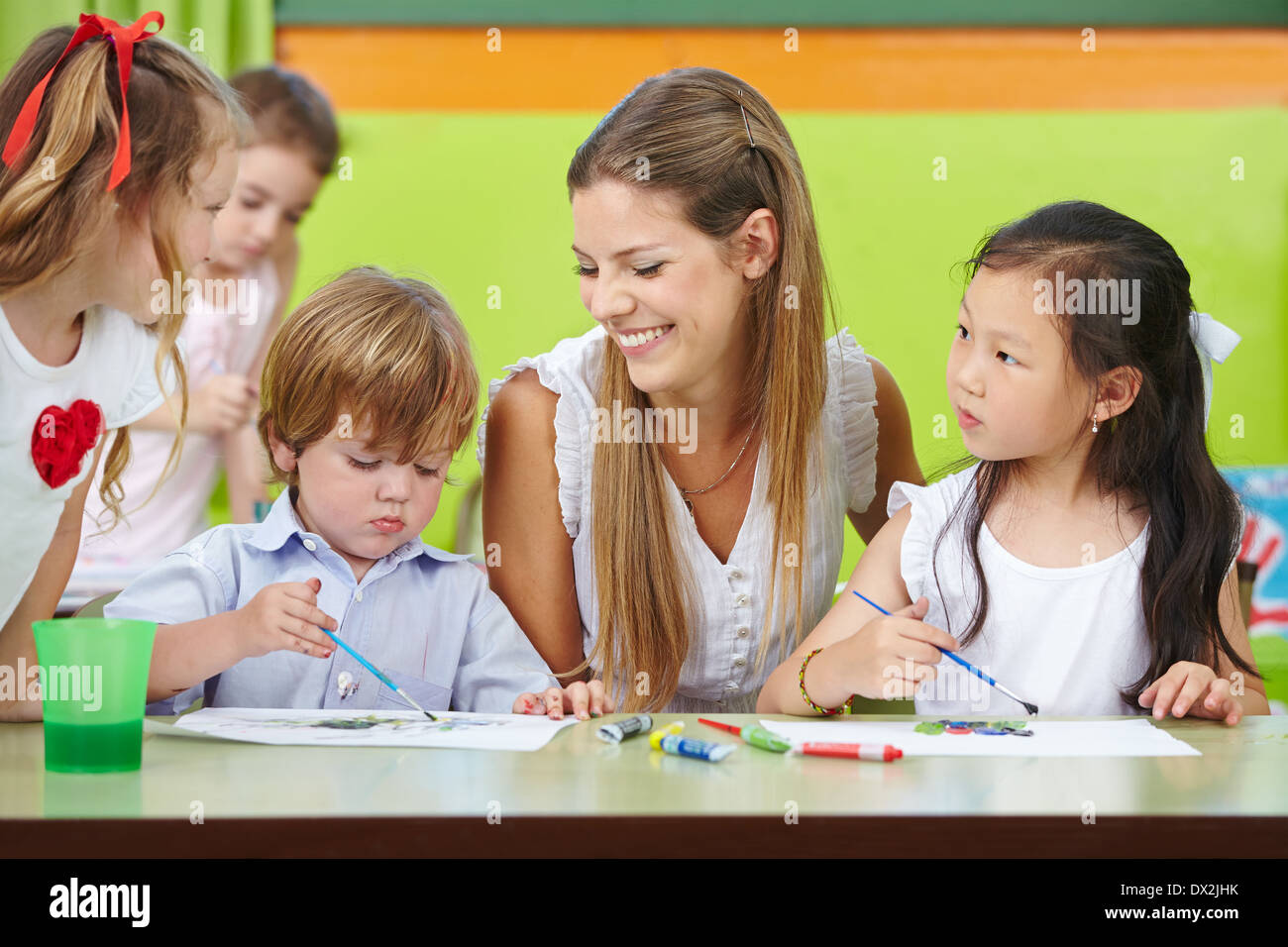 Kinder sind kreative Malerei im Kindergarten mit einem glücklich Kindergärtnerin Stockfoto