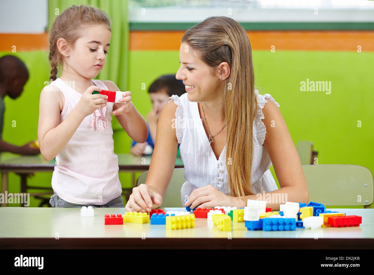 Junge Frau Praktikum in einem Kindergarten und einem Kind zu helfen Stockfoto