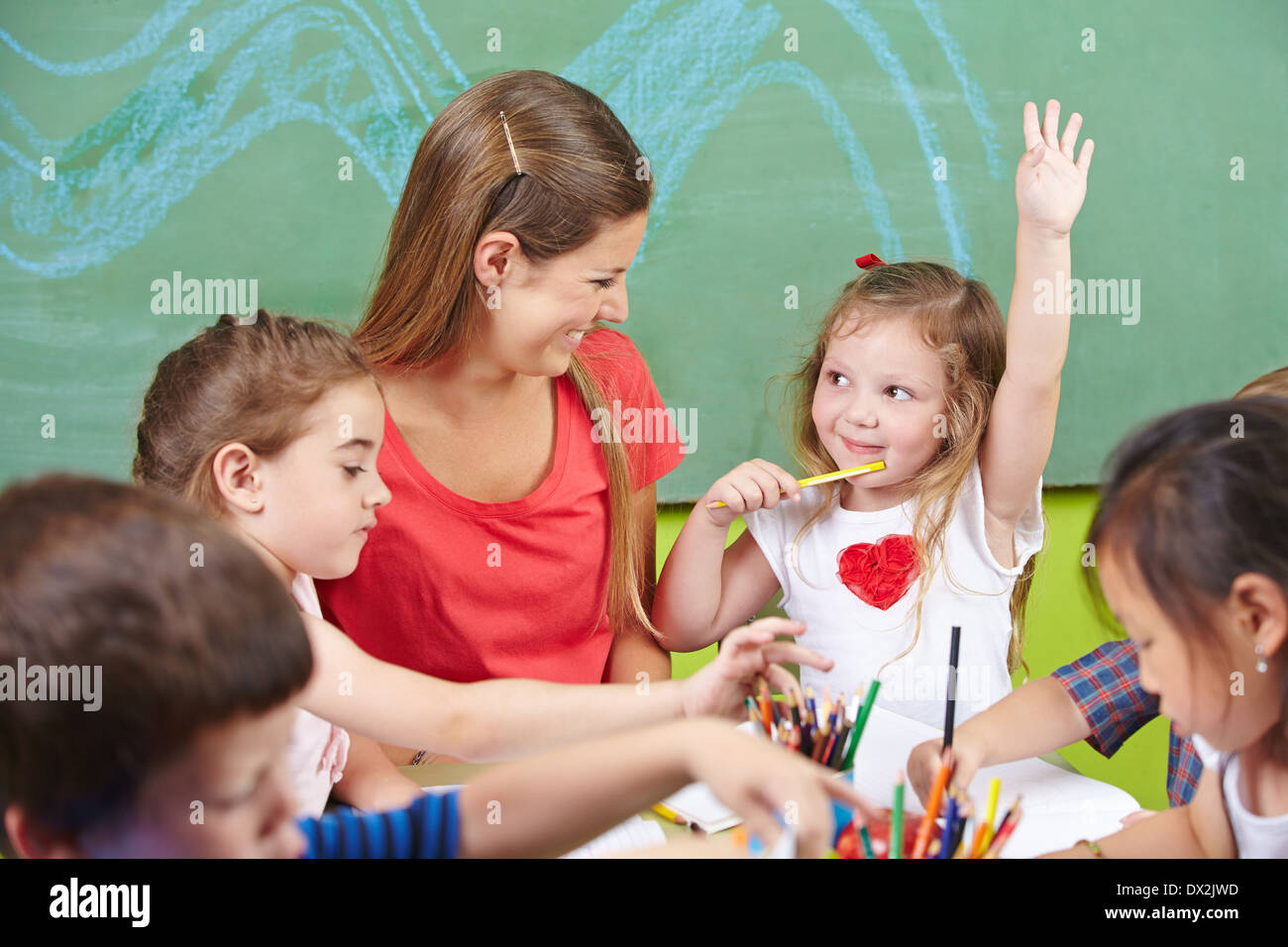 Mädchen, hob ihre Hand in der Vorschule mit ein Bild zu malen Stockfoto