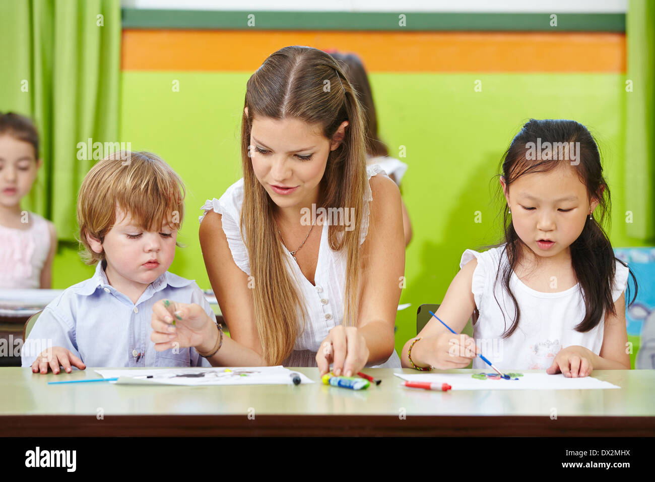 Kinder und Erzieher im Kindergarten mit Pinsel auf Papier malen Stockfoto