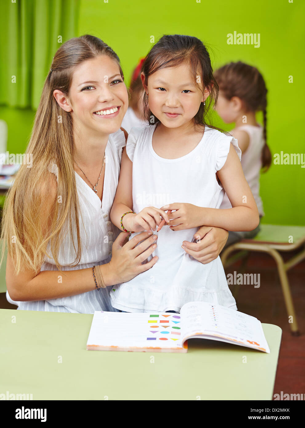 Chinesin mit Kind Pflegedienst im Kindergarten lernen mit einem Buch Stockfoto