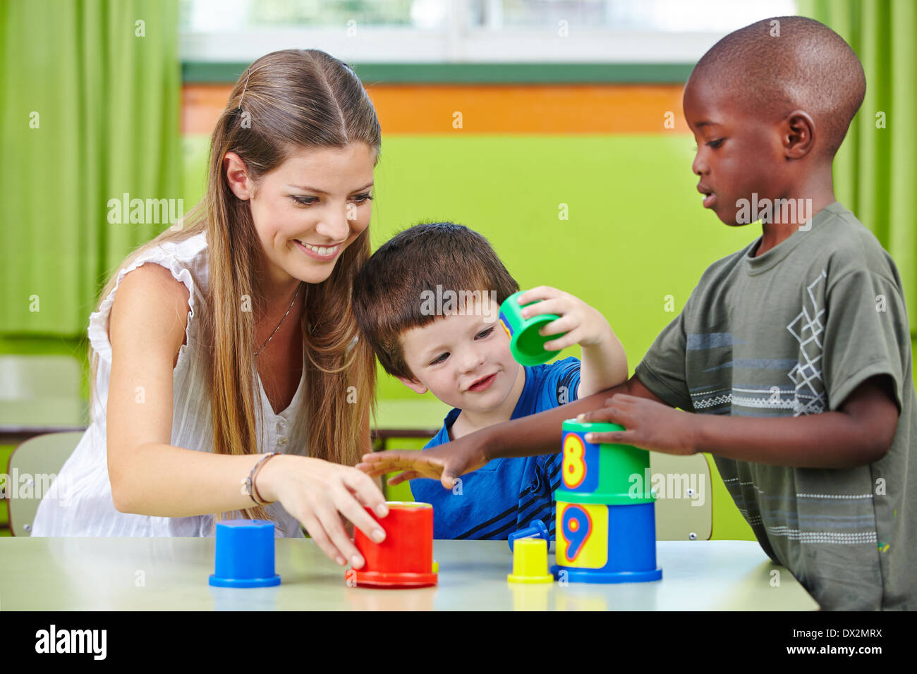 Kindergärtnerin Turm zu bauen, mit Kindern in einem kindergarten Stockfoto