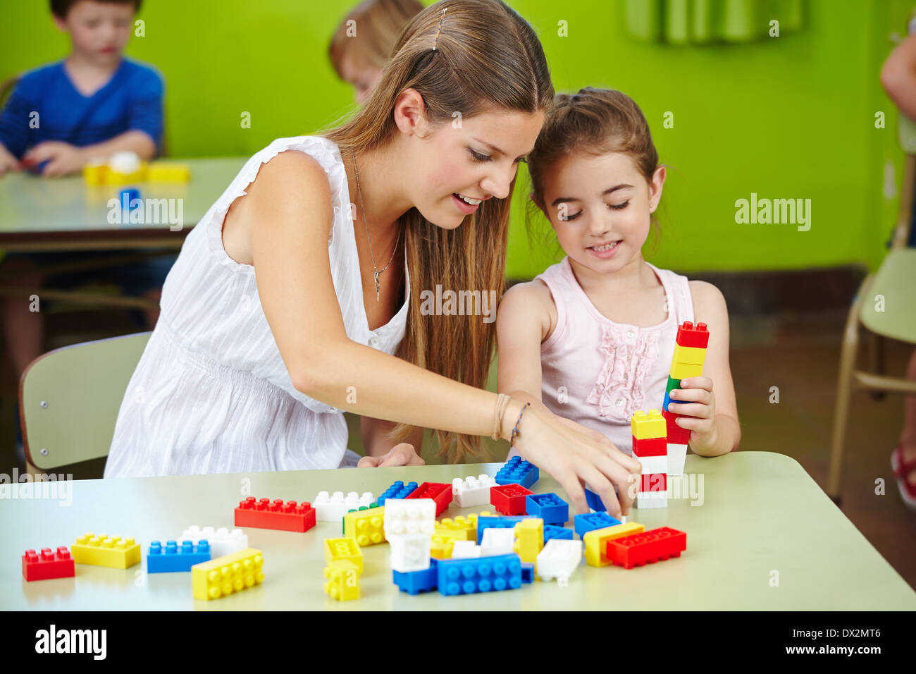 Kindergärtnerin und Mädchen spielen mit bauen von Backsteinen in einem kindergarten Stockfoto