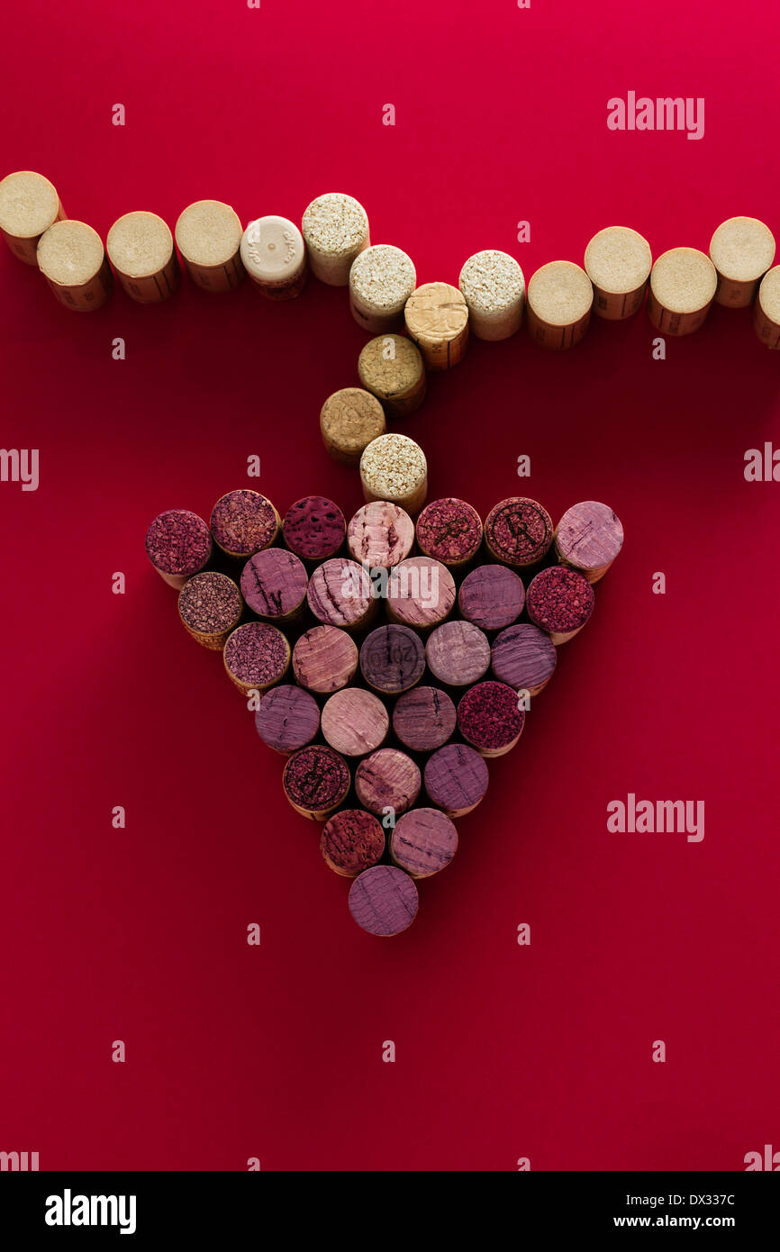 Rote und weiße Weinkorken als ein Bündel von Trauben hängen von einer Rebe auf einem roten Hintergrund, Konzept-Bild für die Weinindustrie angeordnet, Stockfoto