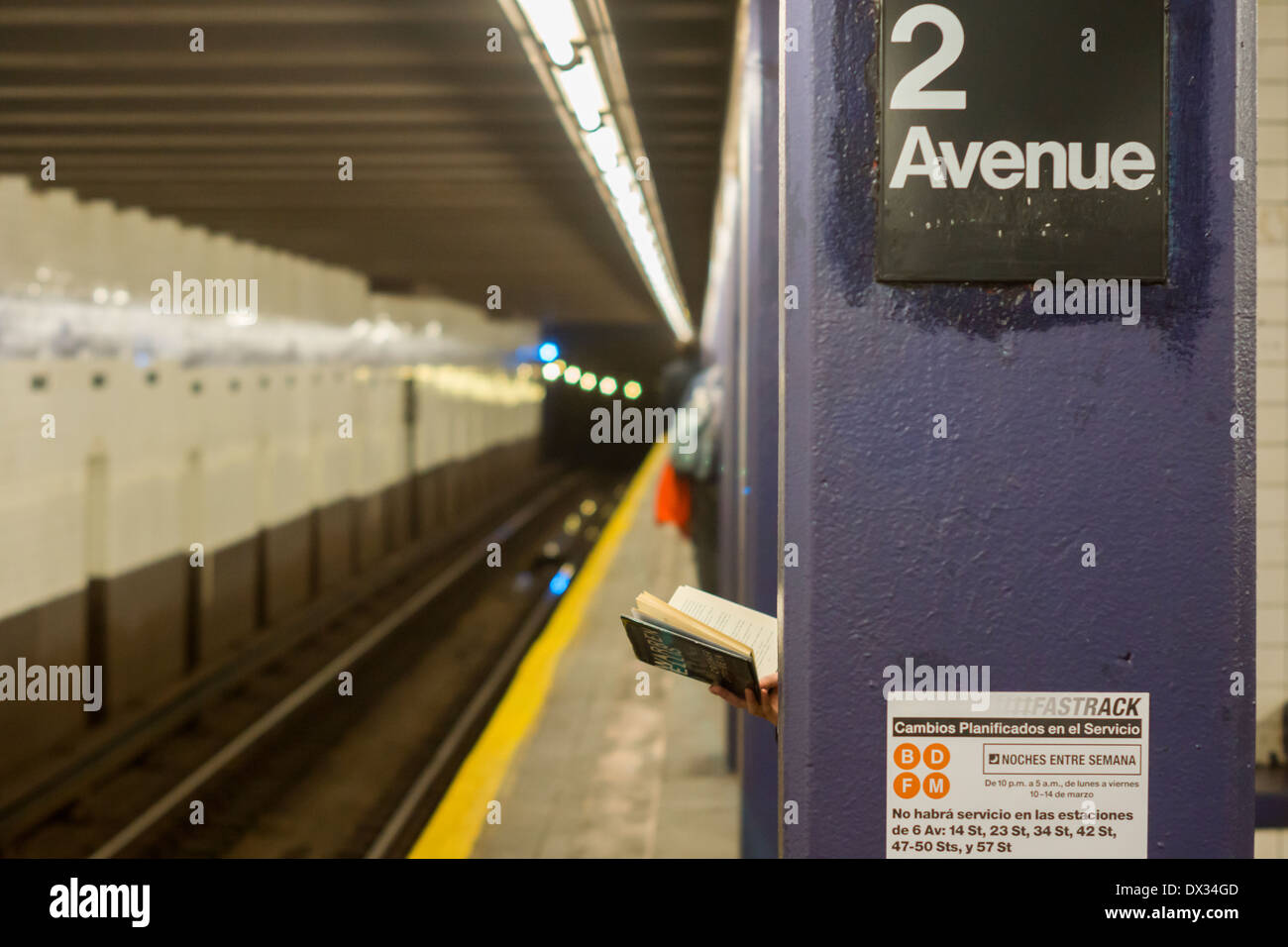 Eine Frau liest einen Hardcover-Buch auf der Second Avenue-Plattform in der New Yorker u-Bahn Stockfoto