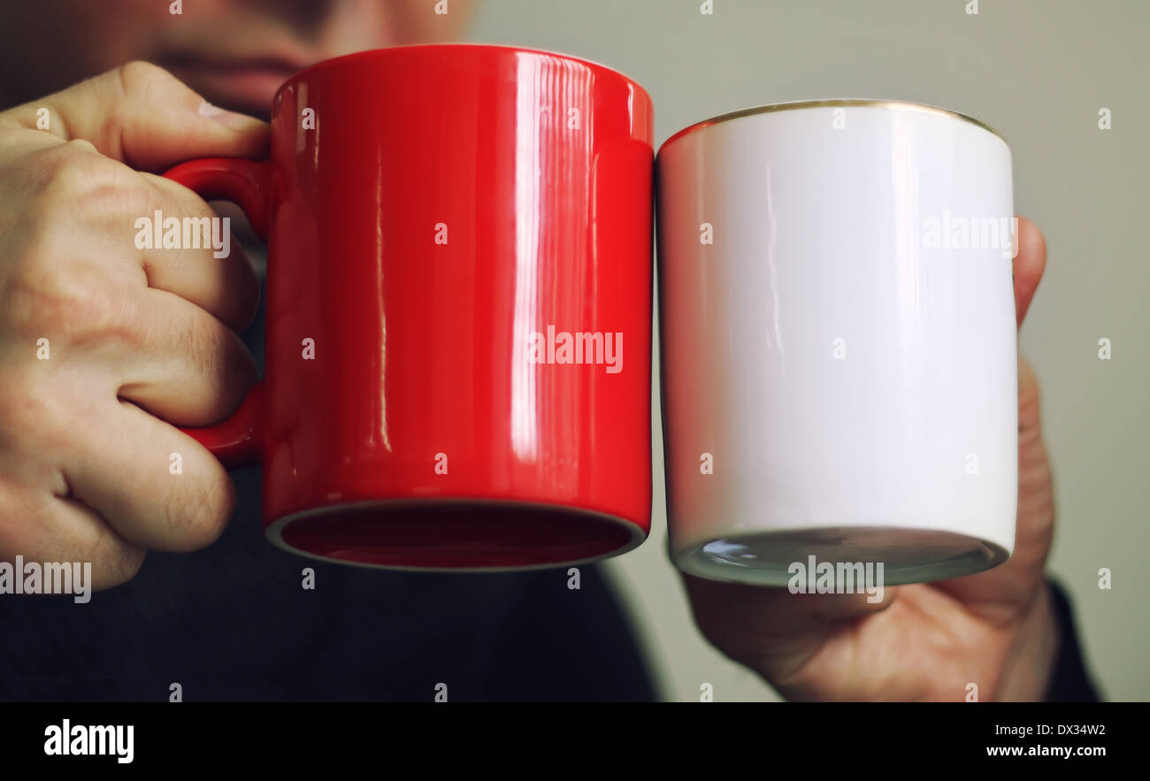 Zwei Männer halten rote und weiße Tassen in ihnen die Hände Stockfoto
