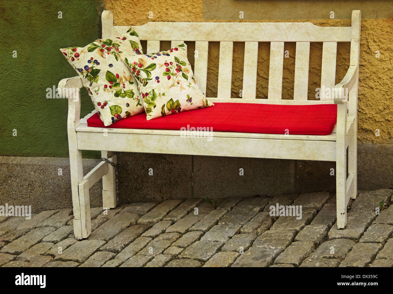 romantische rustikale Holzbank mit Kissen im freien gelbe Wand Stockfoto