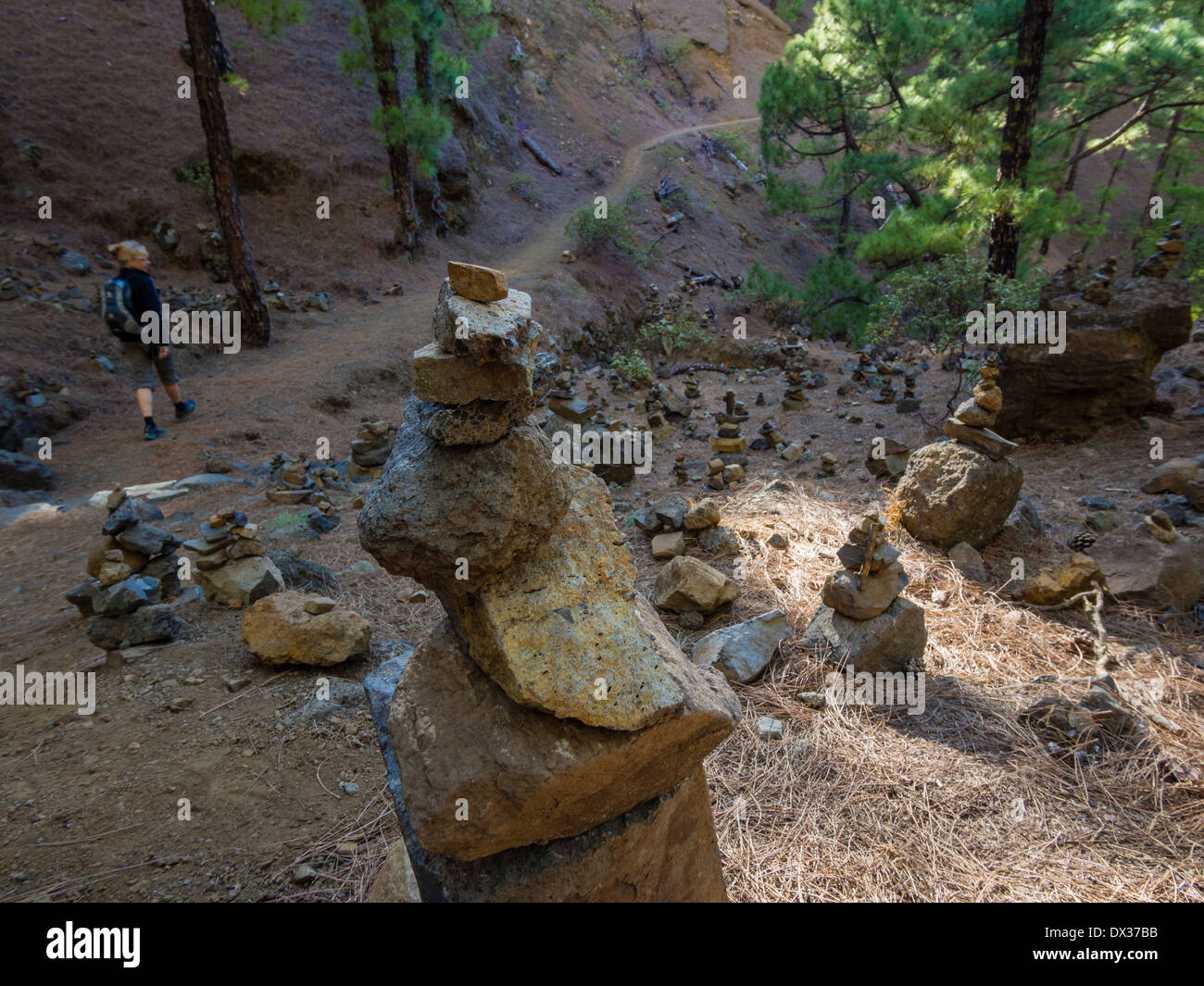 Eine weibliche Wanderer geht Steinhaufen, die auf der Strecke im Nationalpark Caldera de Taburiente stehen. Stockfoto