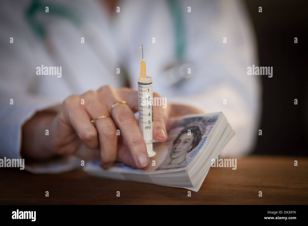 Nahaufnahme einer Ärzte-Hand halten Bargeld und eine Injektionsspritzen Stockfoto