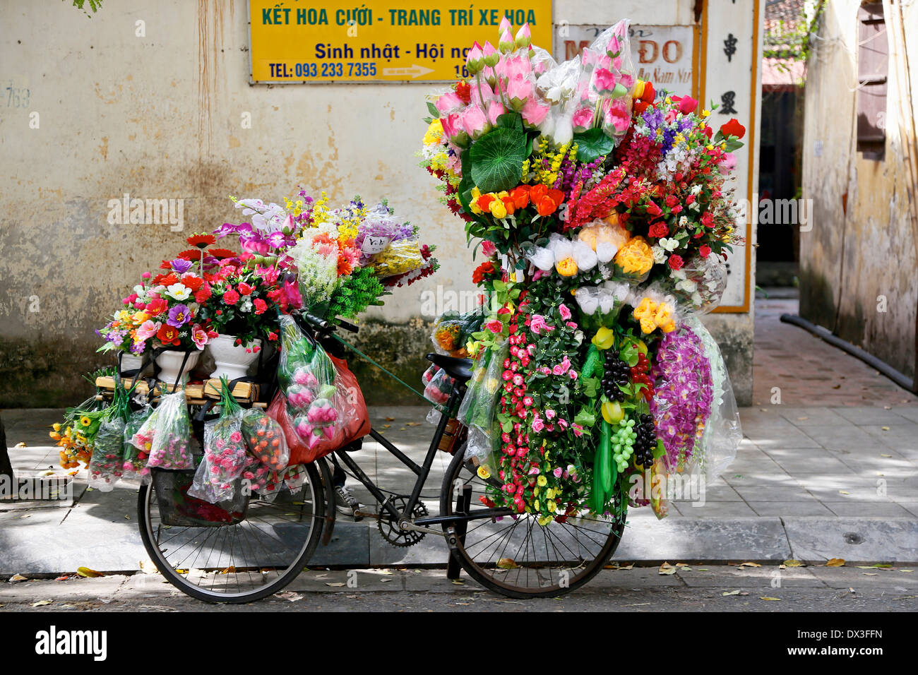 Hanoi Straßenszene. Eine Blumenverkäuferin Fahrrad in der Altstadt von Hanoi. Hanoi, Vietnam, Südostasien Stockfoto