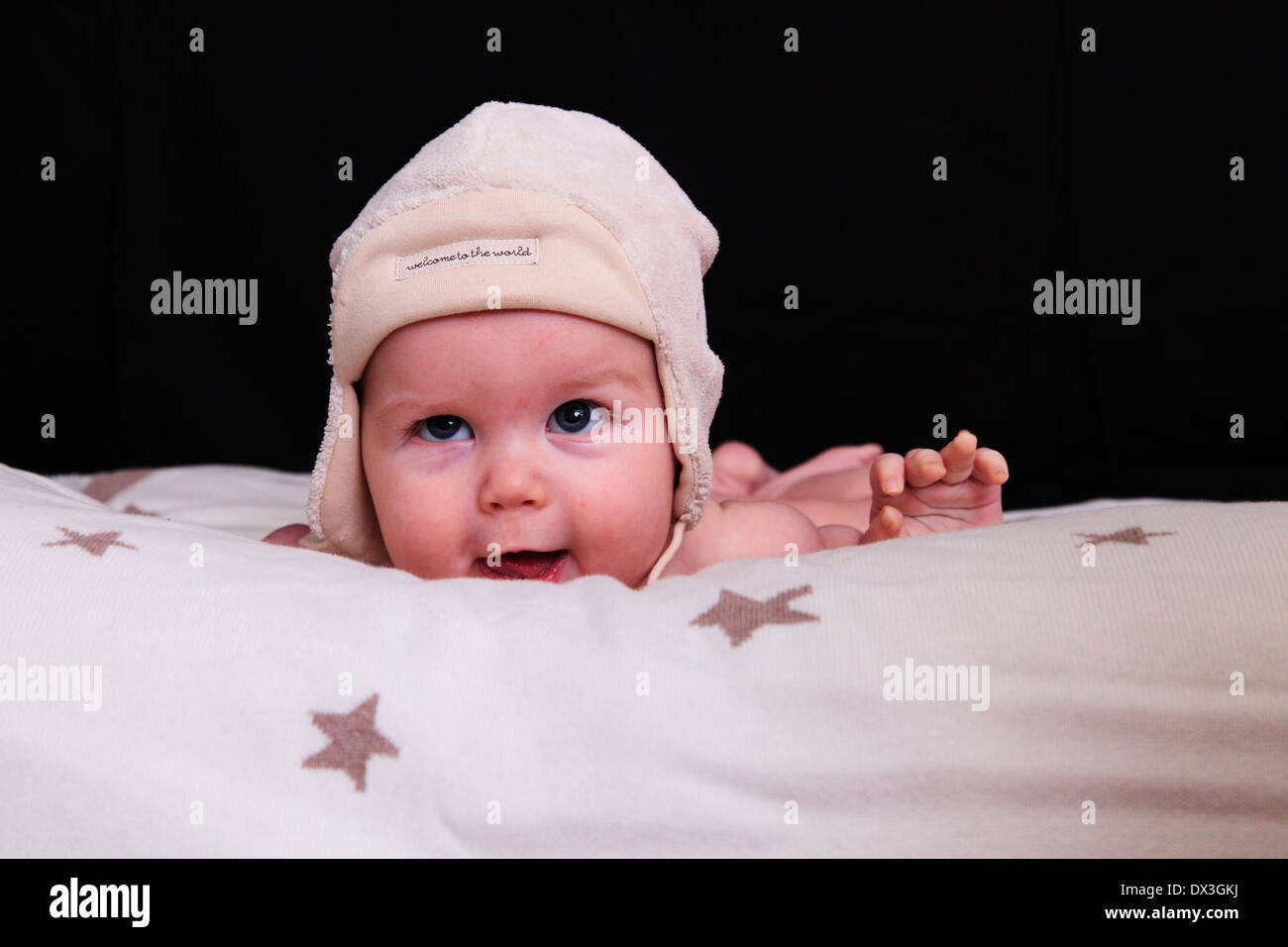 Glückliches Baby auf Decke trägt Wollmütze Stockfoto