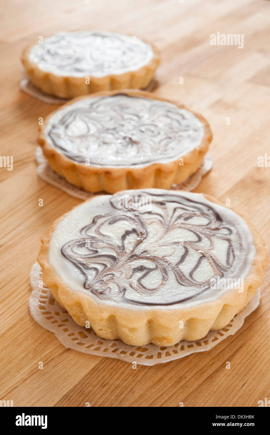 Drei weiße Schokoladen-Käsekuchen Kuchen auf einer hölzernen Theke Stockfoto
