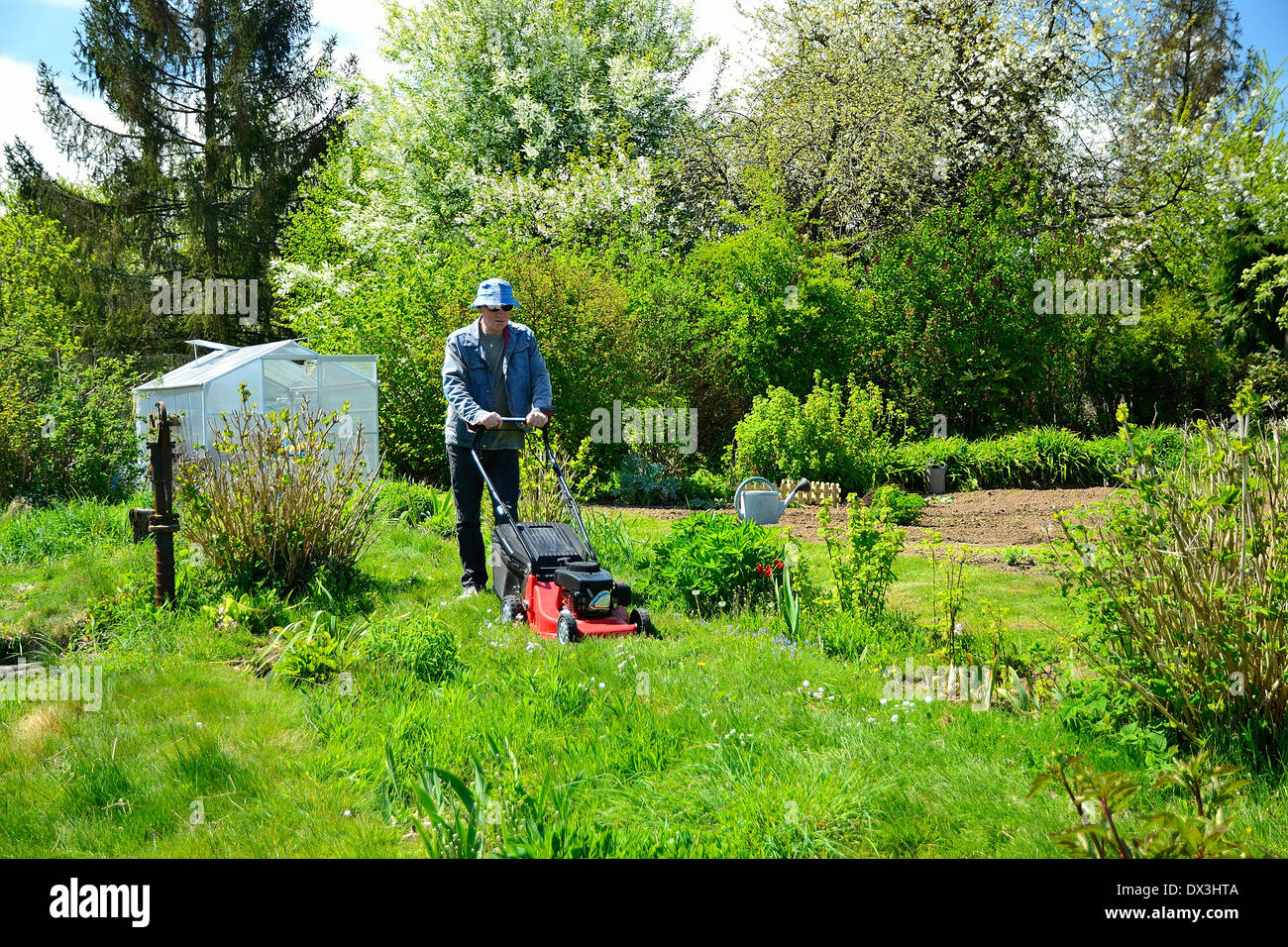 Ein Mann in einem Garten mit Rasenmäher (Mayenne, Land der Loire, Frankreich). Stockfoto