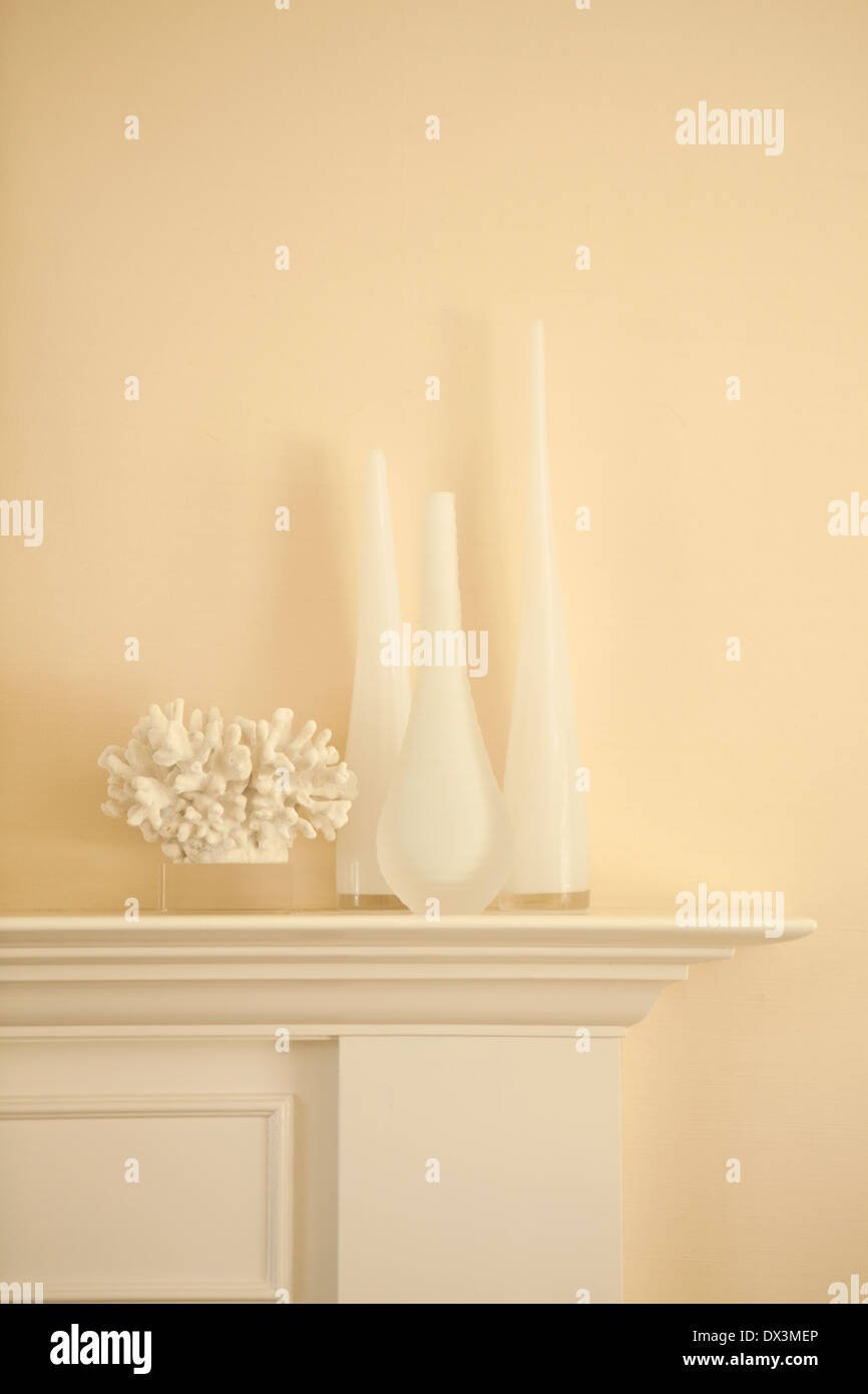 Weiße Vasen und Korallen auf Kaminsims im Wohnzimmer Stockfoto