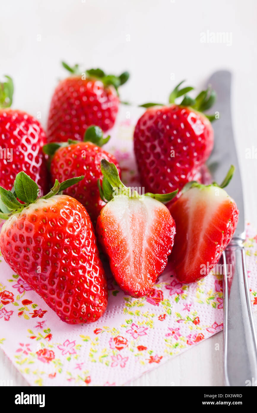 Nahaufnahme von jede Menge frische Erdbeeren und Silber Metall Messer ruht auf dekorative floral serviette Stockfoto