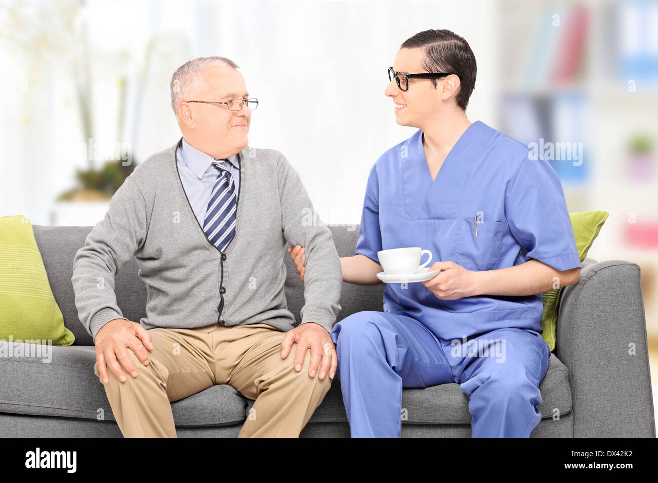 Senioren Erwachsene und männliche Krankenschwester auf Sofa in einem Pflegeheim Stockfoto