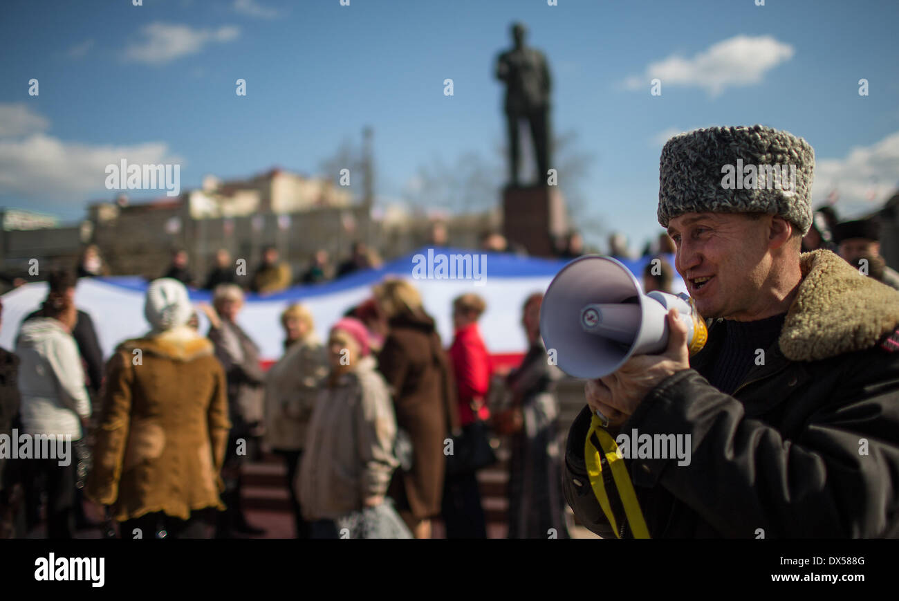 Simferopol, Ukraine. 18. März 2014. Menschen halten eine große russische Fahne vor dem Lenin-Denkmal anlässlich der Rede von russischen Präsidenten Vladimir Putin auf der Krim-Referendum über die Wiedervereinigung mit Russland in Simferopol, Ukraine, 18. März 2014. Putin hält an seinem Kurs trotz Sanktionen von westlichen Nationen. Foto: HANNIBAL/Dpa/Alamy Live News Stockfoto